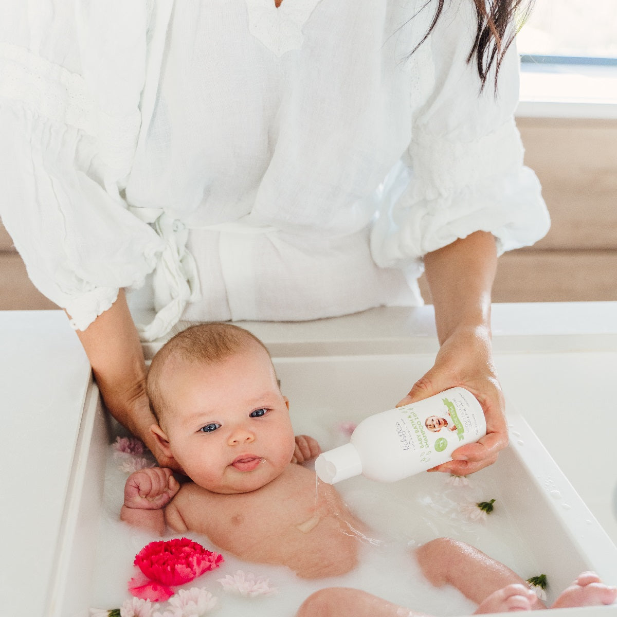 Baby Bath & Shampoo 2 in 1 - Aloe Vera 300ml The Bliss Shelf used during a gentle bath with flowers.