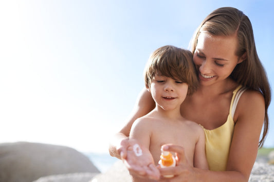 Mum applying sunscreen on her child at the beach, highlighting sunscreen application mistakes for mums.