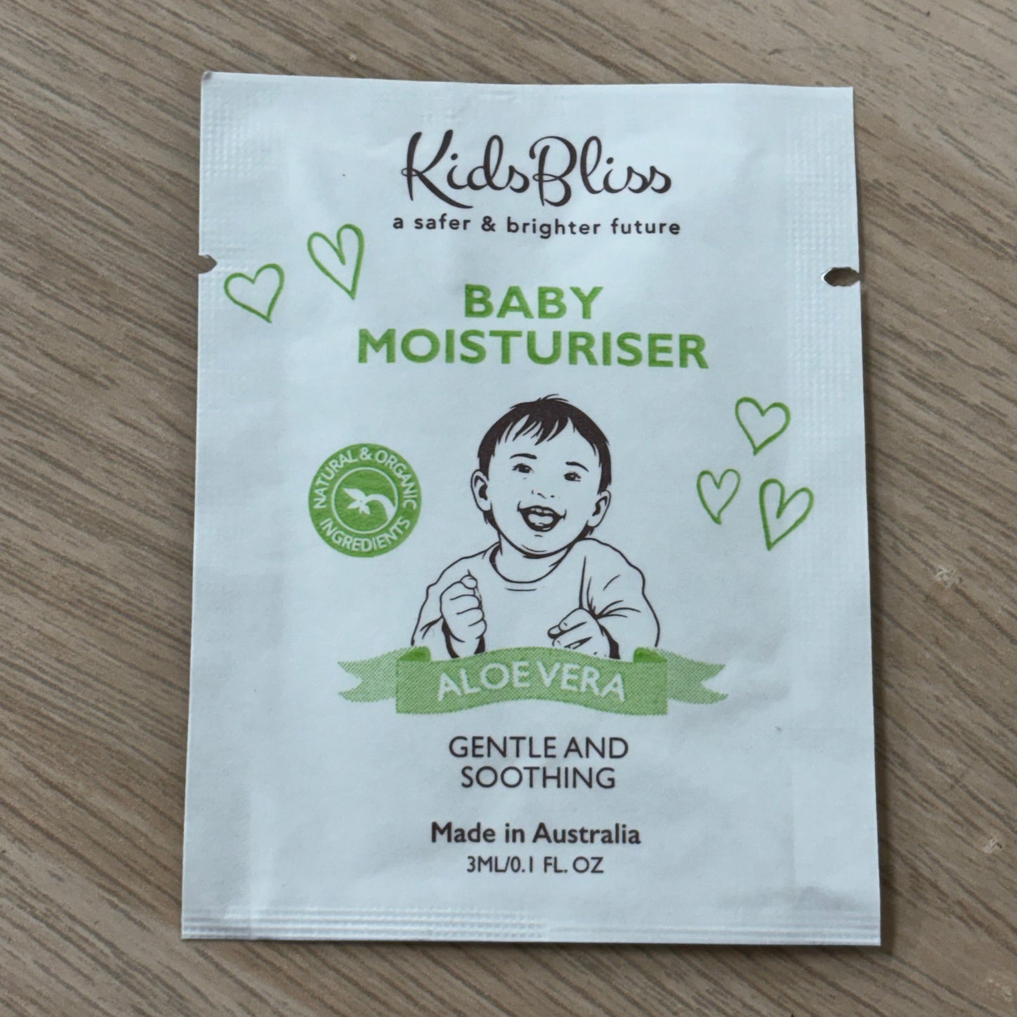 Small white packaging of Kids Bliss baby moisturizer on a wooden surface