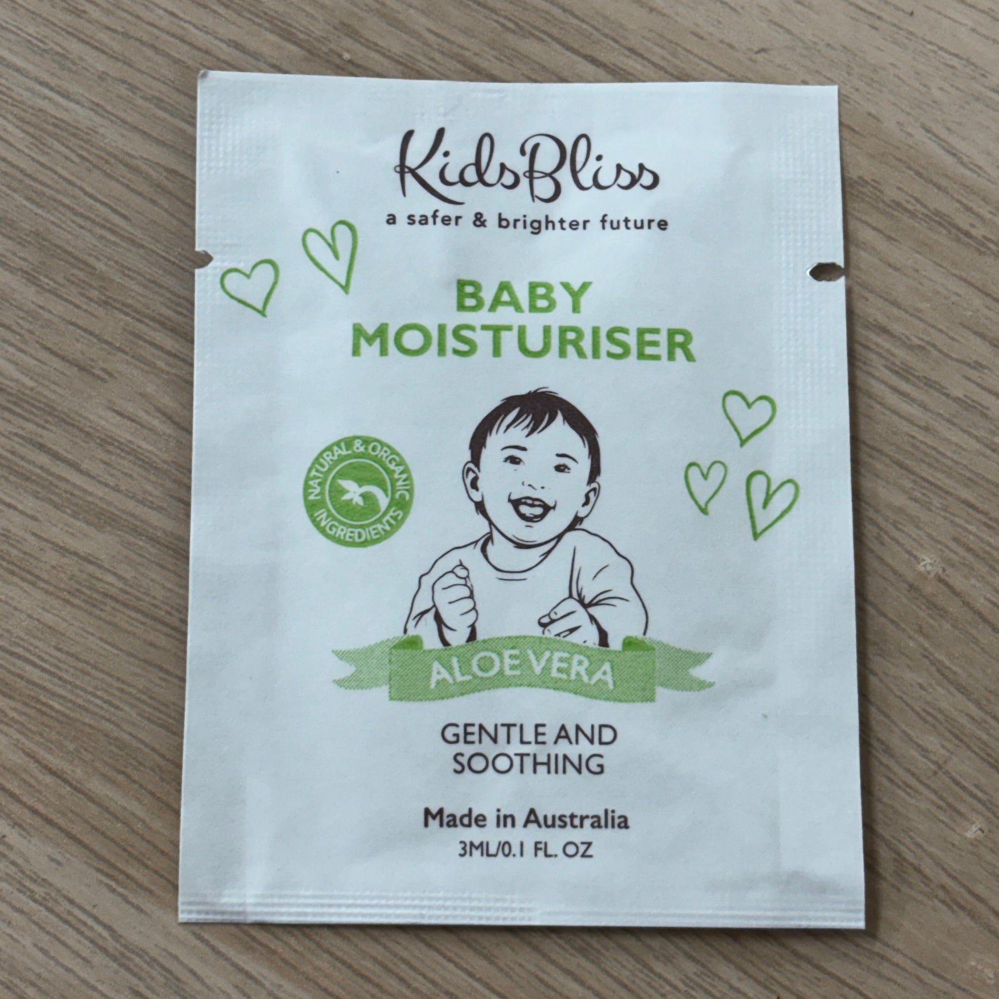 Small white packaging of Kids Bliss baby moisturizer on a wooden surface