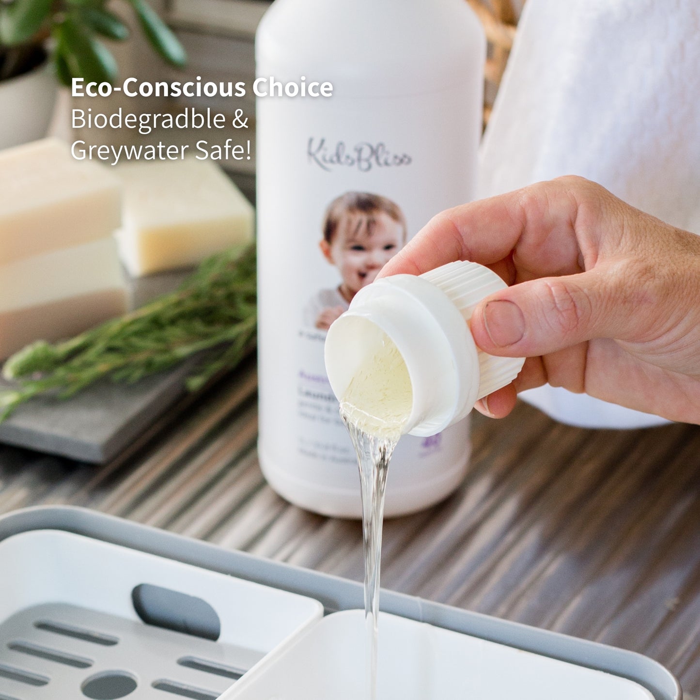 Hand pouring a liquid from a bottle of kidsbliss fabric softener into a container, surrounded by eco-friendly products