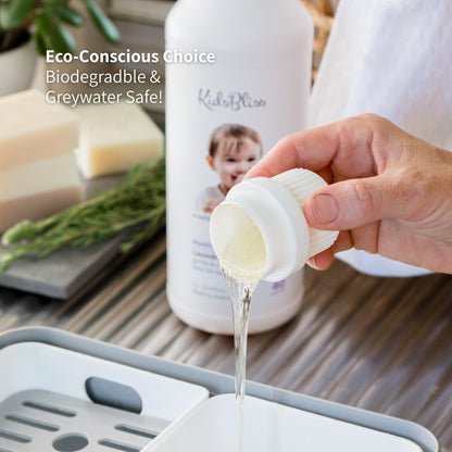 Hand pouring a liquid from a bottle of kidsbliss fabric softener into a container, surrounded by eco-friendly products